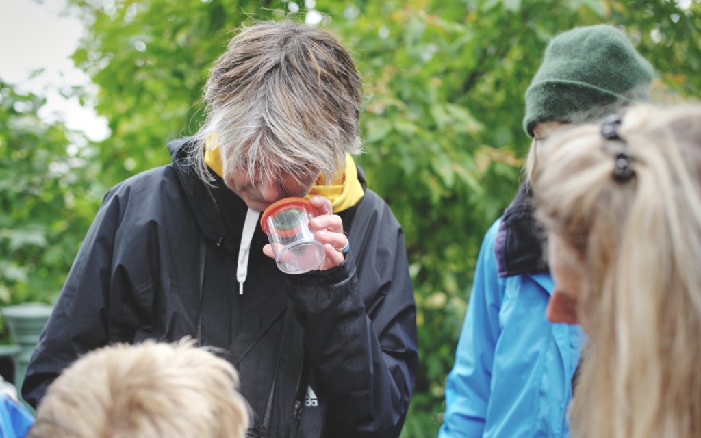 Person schaut in ein Becher und andere Menschen schauen zu